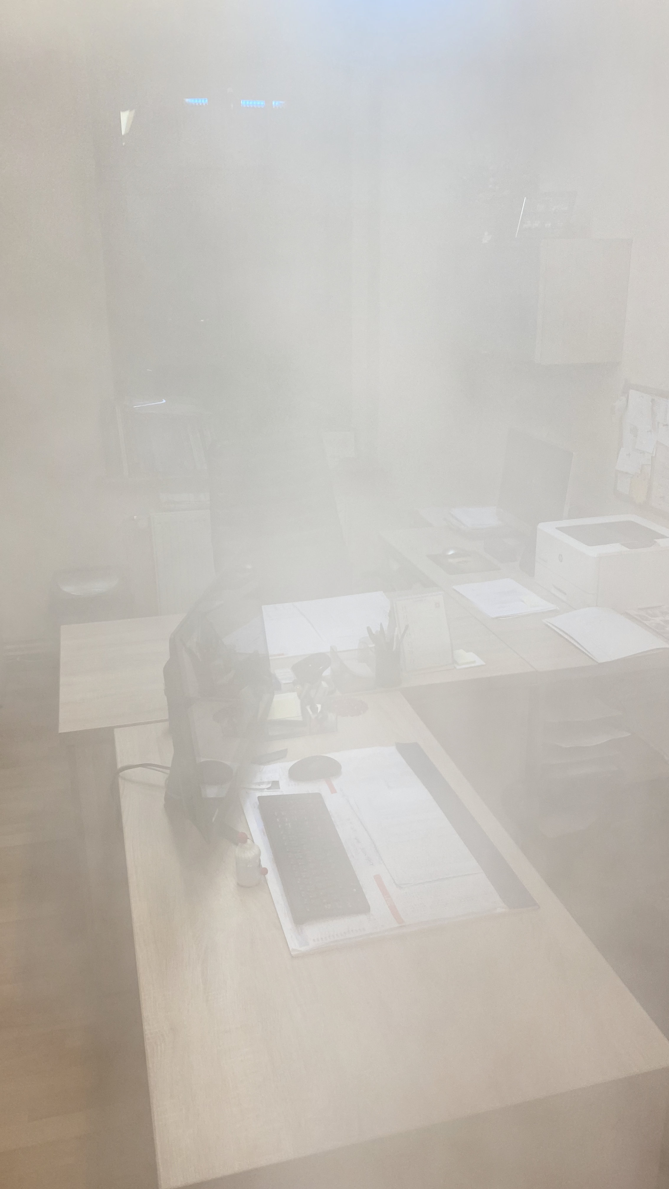 Zamglone biuro z dokumentami, monitorem i drukarką podczas dezynfekcji pomieszczenia.