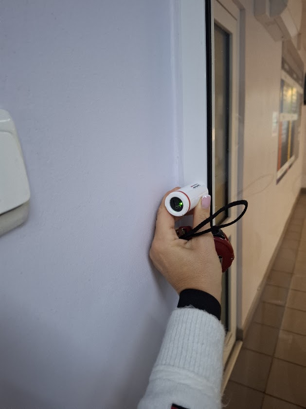 Pomiar przy drzwiach do pomieszczenia za pomocą elektronicznego miernika.