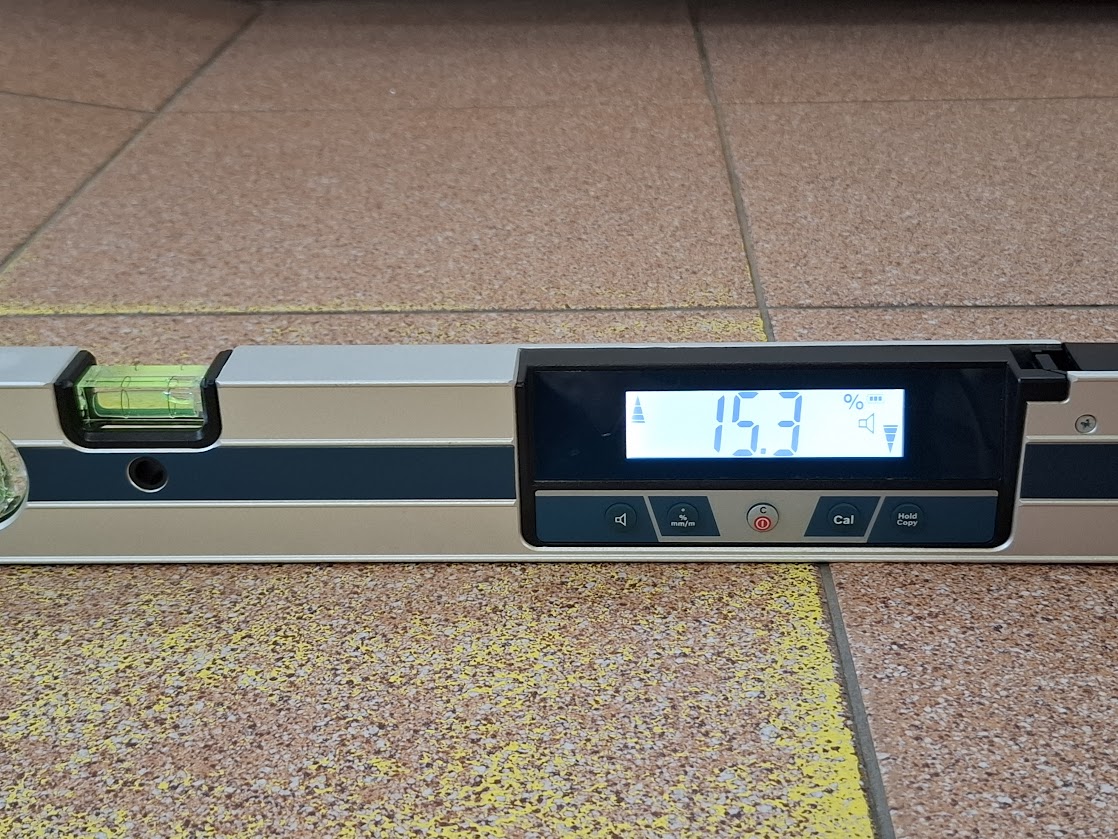 Poziomica elektroniczna mierzy spadek nawierzchni przed wejściem.