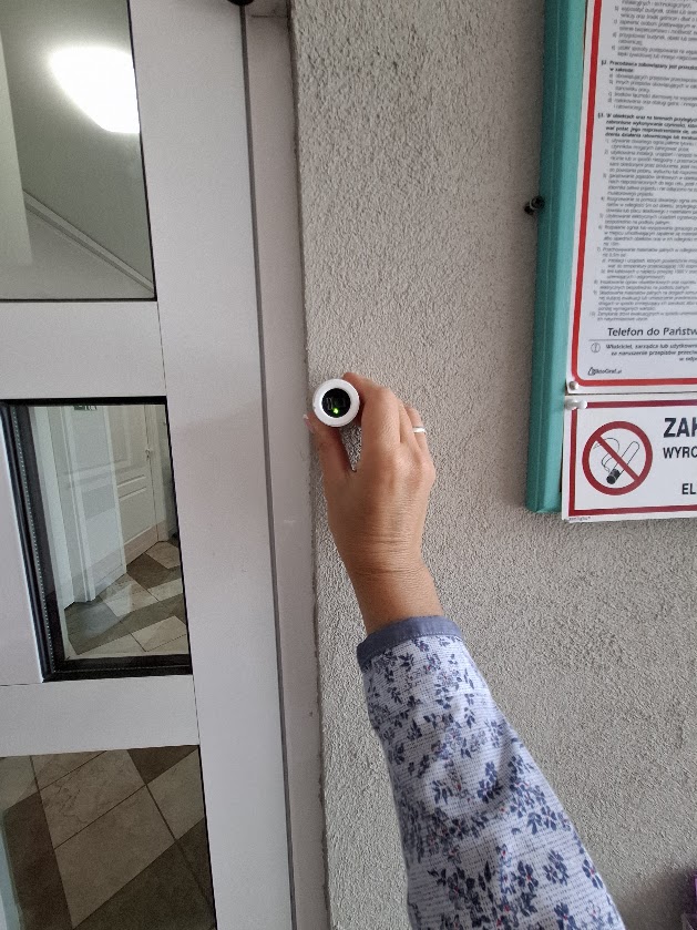 Audytorka mierzy kontrast wokół wejścia do budynku przenośnym miernikiem.