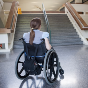 Kobieta na wózku inwalidzkim patrząca na schody pod które nie może wjechać